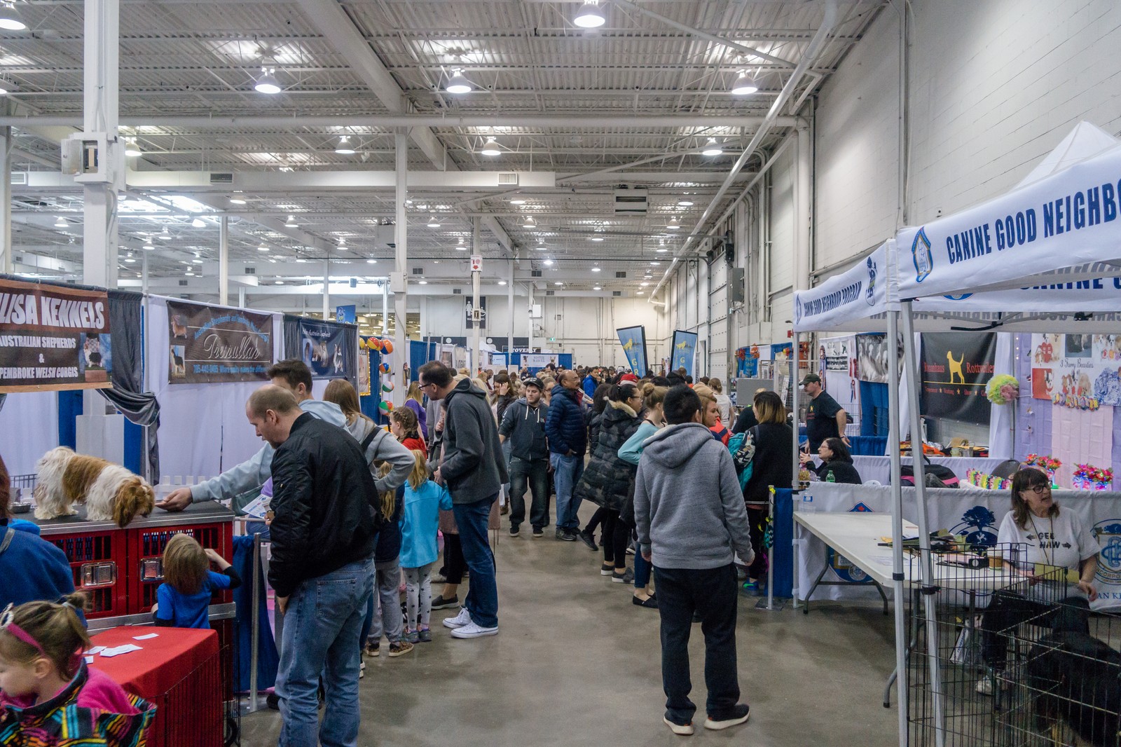A busy indoor expo hall lined with exhibitor booths and attendees.